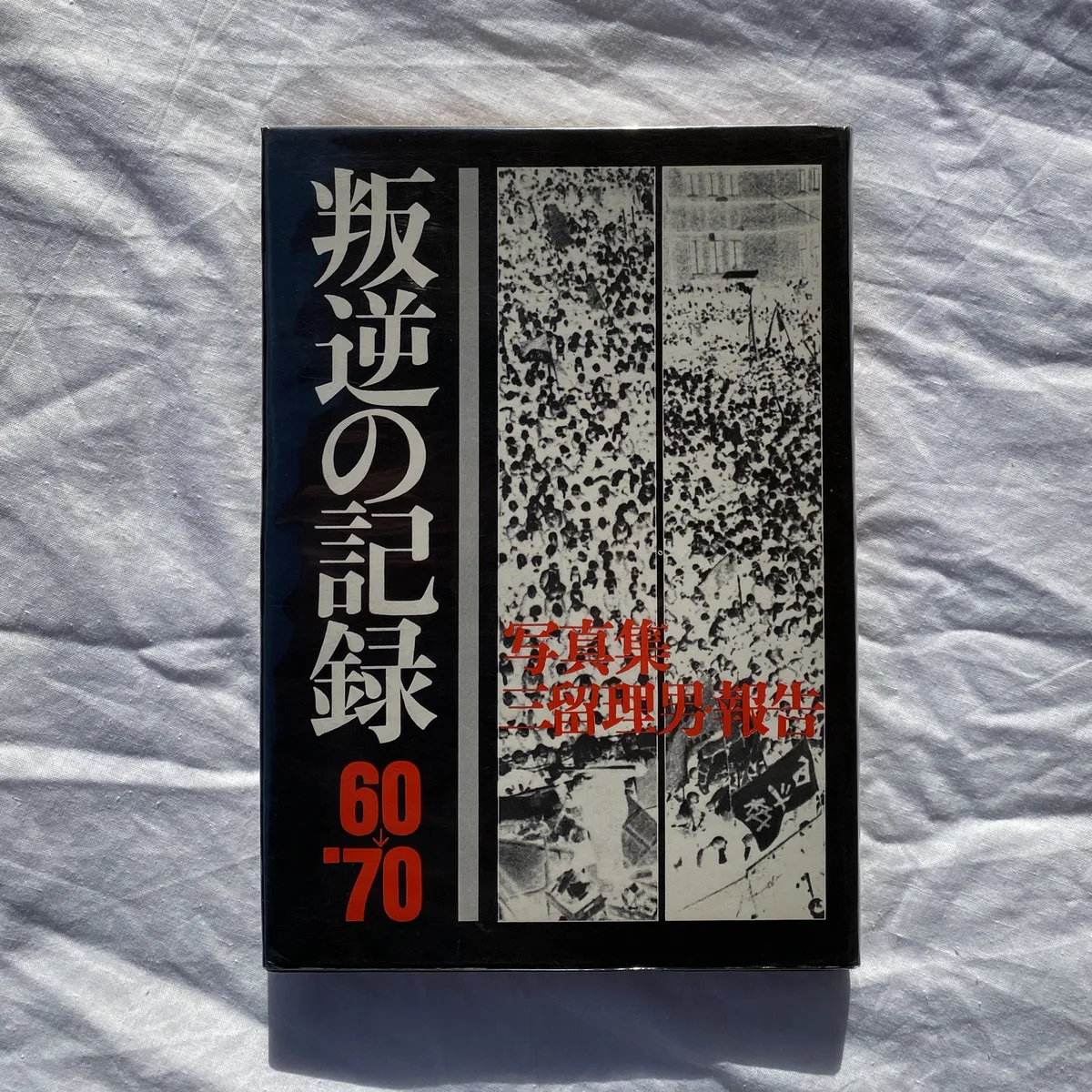 Portada del llibre "Records of Revolts 60-70" de Tadao Mitome. És una portada de color de fons negre, amb molts caràcters japonesos en color blanc i els números 60-70 en vermell. En la meitat dreta es pot veure una imatge invertida d'una manifestació.