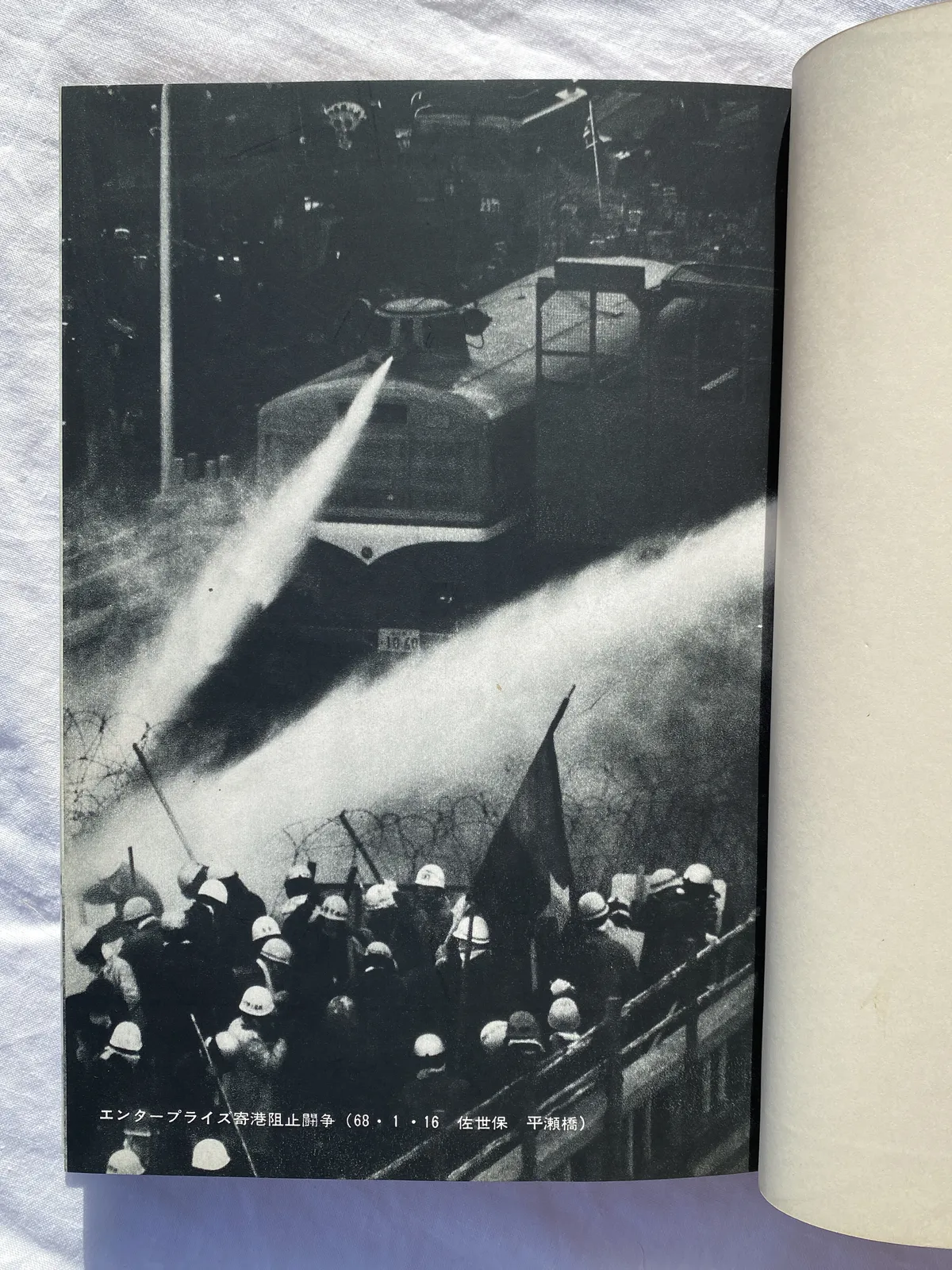 Fotografia en blanc i negre d'un camió cisterna tirant un raig d'aigua contra els manifestants.